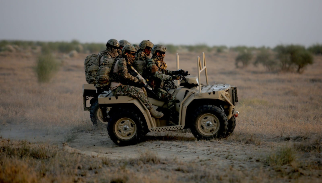 Special Forces unit operating tactical ATV ground vehicle with autonomous perception systems in desert terrain